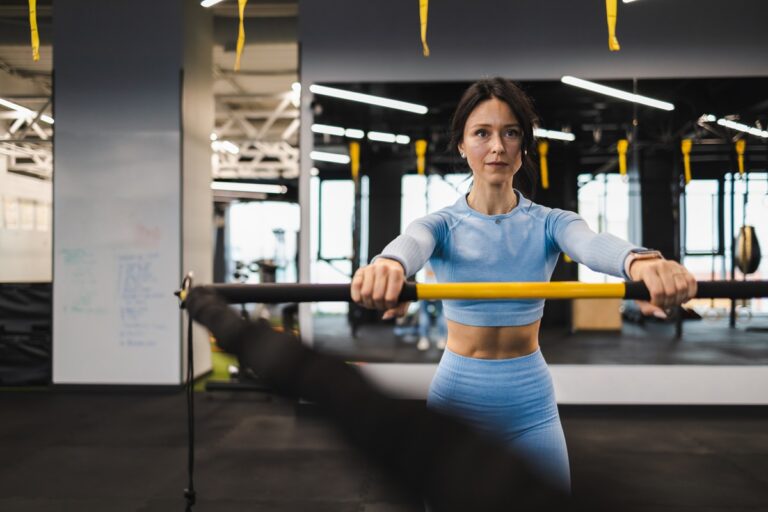 Fitness woman is training with a trx rip trainer in the gym